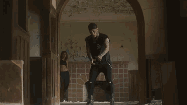 a man in a black shirt is standing in a hallway with a woman behind him