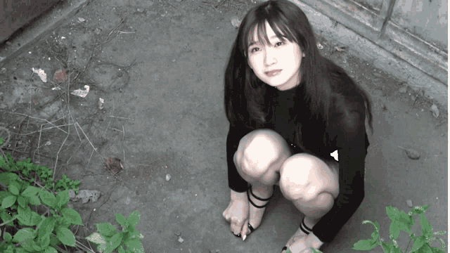 a woman is squatting down on the ground with her legs crossed