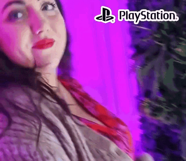a woman is standing in front of a purple wall with a playstation logo behind her
