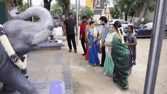a group of people are standing in front of an elephant statue .