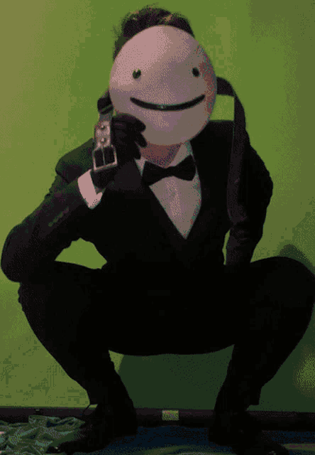 a man in a tuxedo is squatting down with a mask on his head