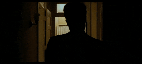 a silhouette of a man talking on a telephone in a dark hallway .