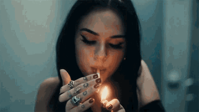 a young woman is lighting a cigarette with a lighter .