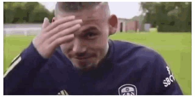 a man is covering his face with his hand on a field .
