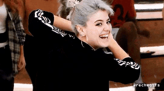 a woman with a ponytail is smiling and holding her hair in a ponytail
