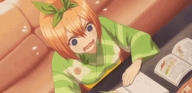 a girl in a green kimono is sitting at a table with a book open