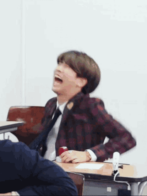 a man in a plaid jacket and tie is laughing