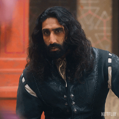 a man with long hair and a beard is wearing a jacket that says netflix on it