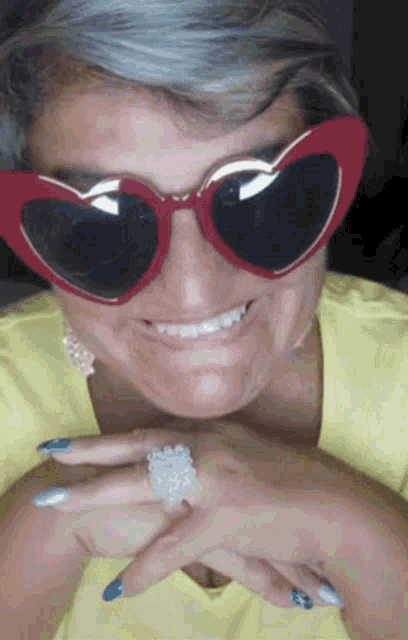 a woman wearing heart shaped sunglasses is smiling