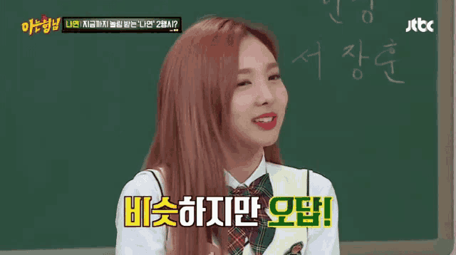 a girl with red hair is sitting in front of a blackboard with chinese writing on it