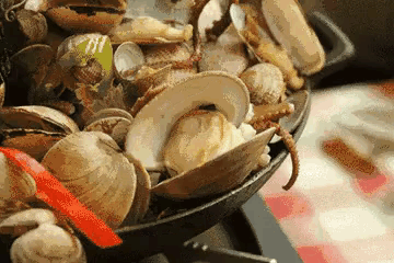 a close up of a bowl of clams with a red ribbon on the side