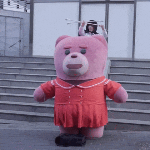 a pink teddy bear in a red dress is standing on a set of steps