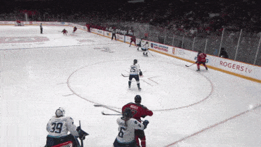 a hockey game is being played in front of a rogers tv sign