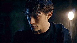 a young man with wet hair is standing in front of a street light at night .