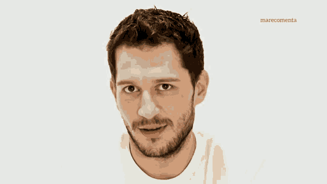 a man with a beard is smiling in front of a white background with the name marecomenta on it