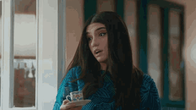 a woman is holding a cup of coffee in her hand .
