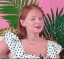 a woman in a white and black polka dot dress is smiling .