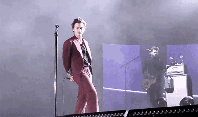 a man in a suit is singing into a microphone on stage .
