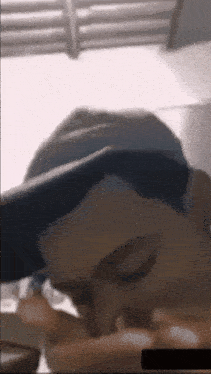 a man wearing a baseball cap is eating a piece of pizza