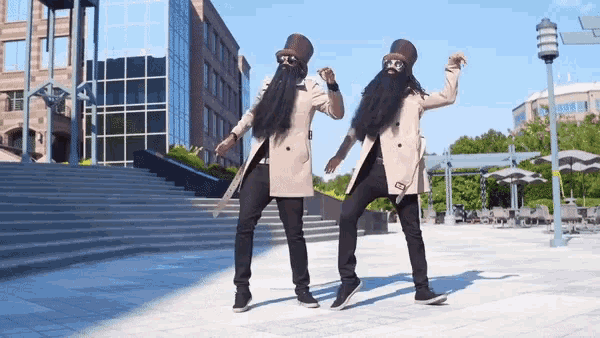 two men in trench coats and hats are dancing