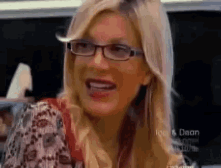 a woman wearing glasses and a floral shirt smiles