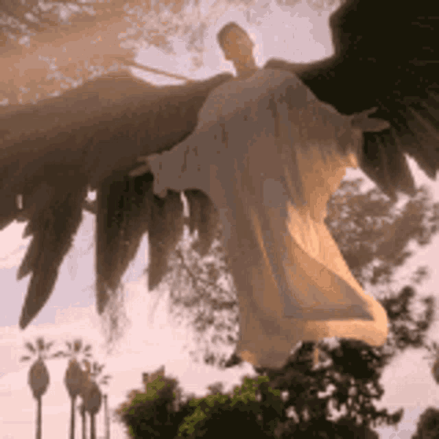 a statue of a man with wings is flying through the air