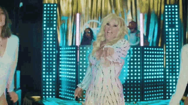 a woman in a white dress is dancing on a stage in front of a crowd of people .
