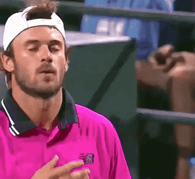 a man wearing a pink shirt and a white hat with the letter b on it