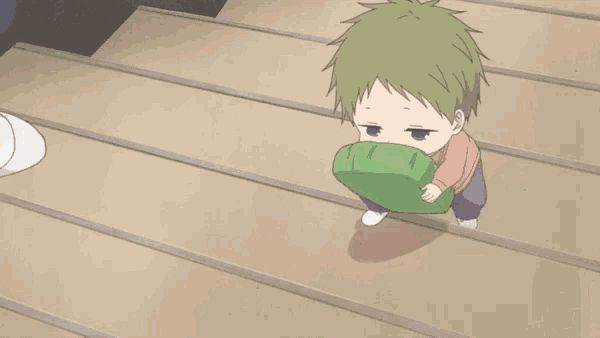 a little boy is walking down a set of stairs while holding a green bag in his mouth .
