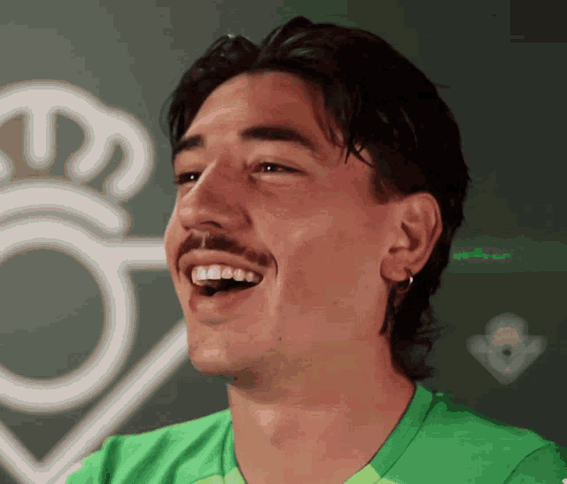 a man with a mustache and a green shirt smiles