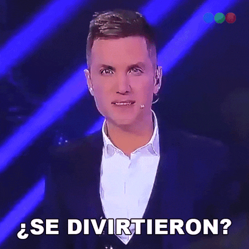 a man in a suit stands in front of a microphone and says se divertieron