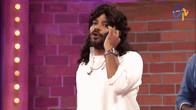 a man with long hair and a beard talking on a cell phone