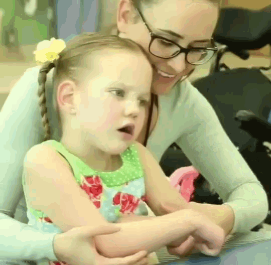 a woman wearing glasses is holding a little girl in her lap