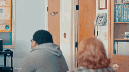 a man and a woman are sitting in a room in front of a closet .