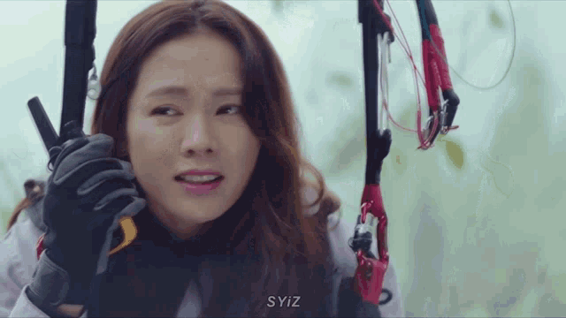 a woman holding a parachute with syiz written on the bottom right
