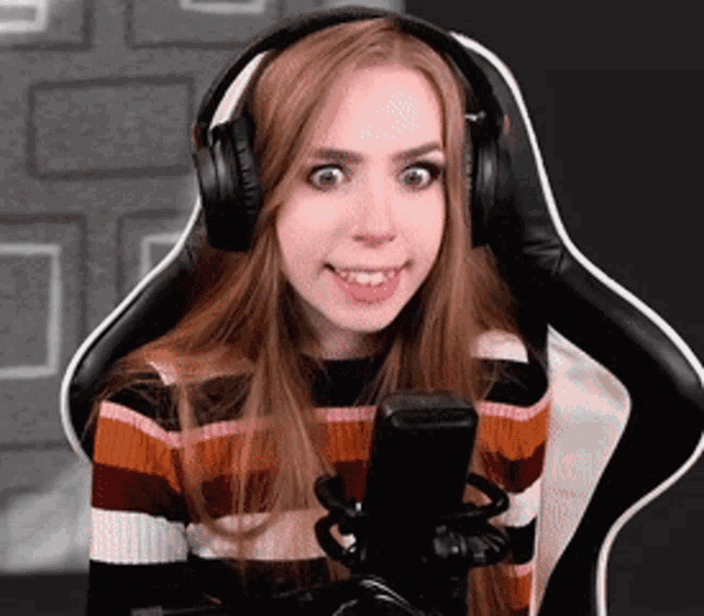 a woman wearing headphones and a striped sweater is sitting in front of a microphone .