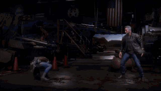 a man in a superhero costume is holding a gun and shooting it at another man in a dark room .