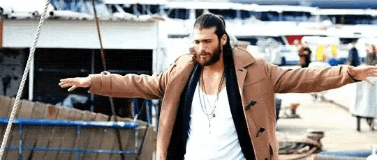 a man with long hair and a beard is standing with his arms outstretched