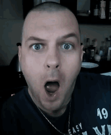 a man wearing a black shirt that says easy on it is making a surprised face