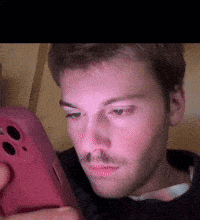 a man with a mustache is looking at a pink cell phone