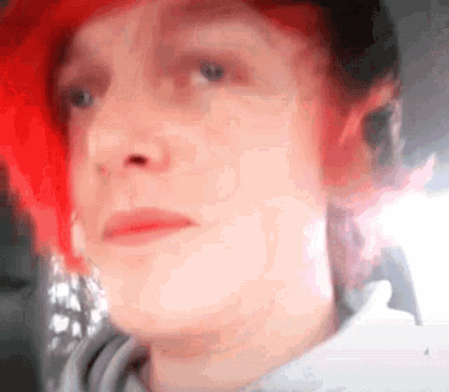 a close up of a person 's face with red hair and a gray shirt .