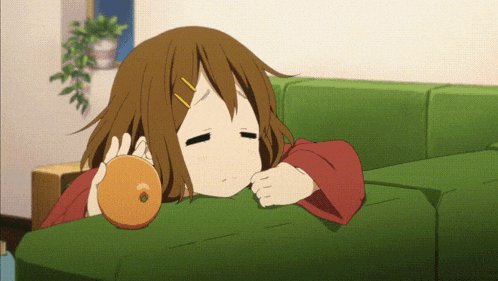a girl laying on a green couch holding an orange in her hand
