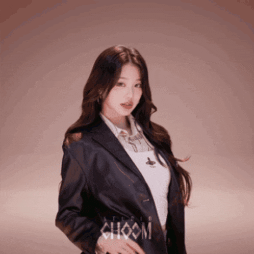 a woman is wearing a black jacket and a white shirt with the word choom on it
