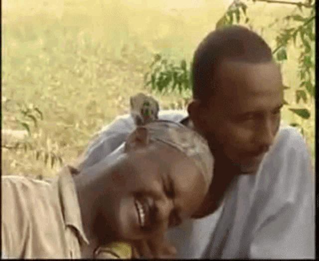 a man and a woman are laying in a field and the woman is smiling .
