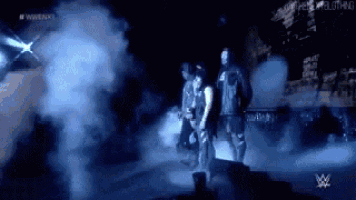 a group of wrestlers are walking on a stage in the dark .