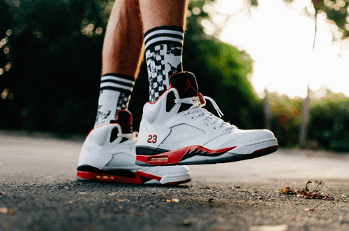 a person wearing a pair of white and red sneakers with the number 23 on them