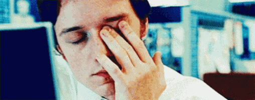 a man in a white shirt is rubbing his eyes .