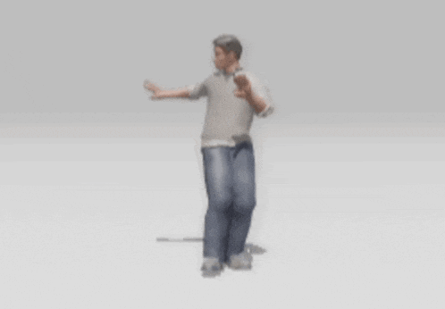 a man in a grey shirt and blue jeans is standing with his hands outstretched