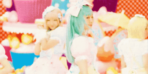 a girl with blue hair is standing in front of a cake .