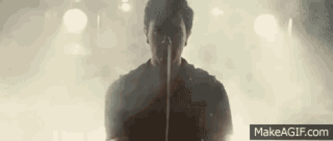 a man is singing into a microphone on a stage in front of a crowd .